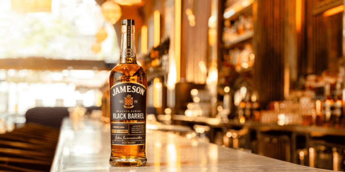 Jameson Black Barrel bottle on a marble bar top in a warmly lit whiskey bar
