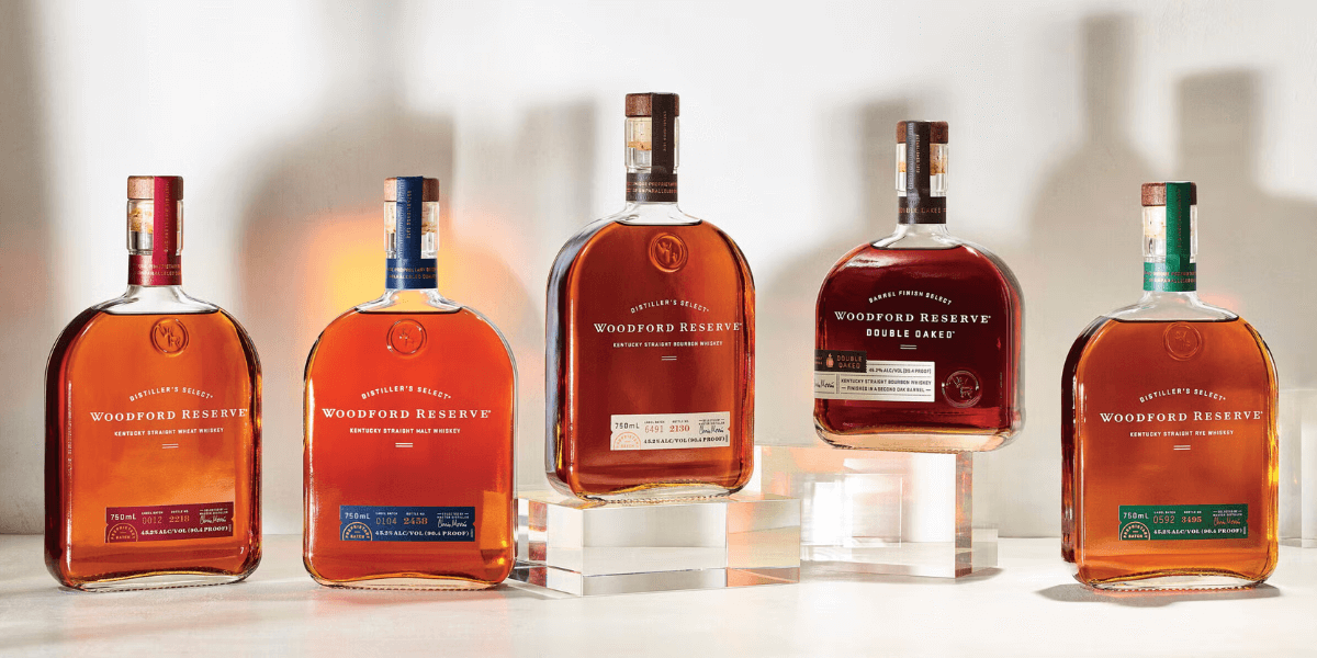 Bottle of Woodford Reserve Kentucky Straight Bourbon standing upright on a wooden table with warm lighting in the background.