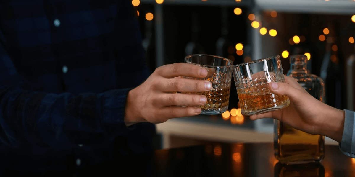 two men holding a glass of whiskey in their hands and cheersing