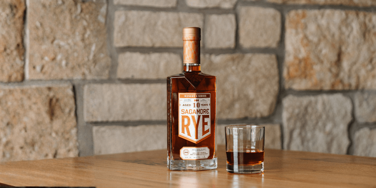 Bottle of Sagamore 10-Year Rye Whiskey on a table with a glass half full 