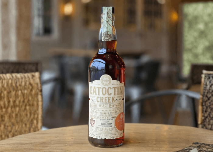 Bottle of Catoctin Creek Members-Only Release whiskey placed on a wooden surface in front of a rustic background