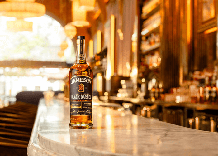 Jameson Black Barrel bottle on a marble bar top in a warmly lit whiskey bar
