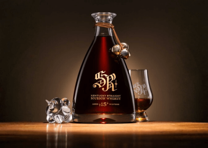 Fathertime Santa’s Reward 15‑Year Kentucky Straight Bourbon in an etched crystal decanter with branded glass, photographed on a wooden surface with warm holiday lighting.