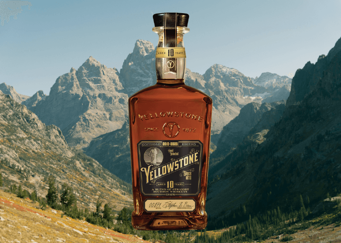 Bottle of Yellowstone Limited Edition 2025 Bourbon displayed in front of a rugged mountain landscape, emphasizing its 10-year aging and anniversary release.